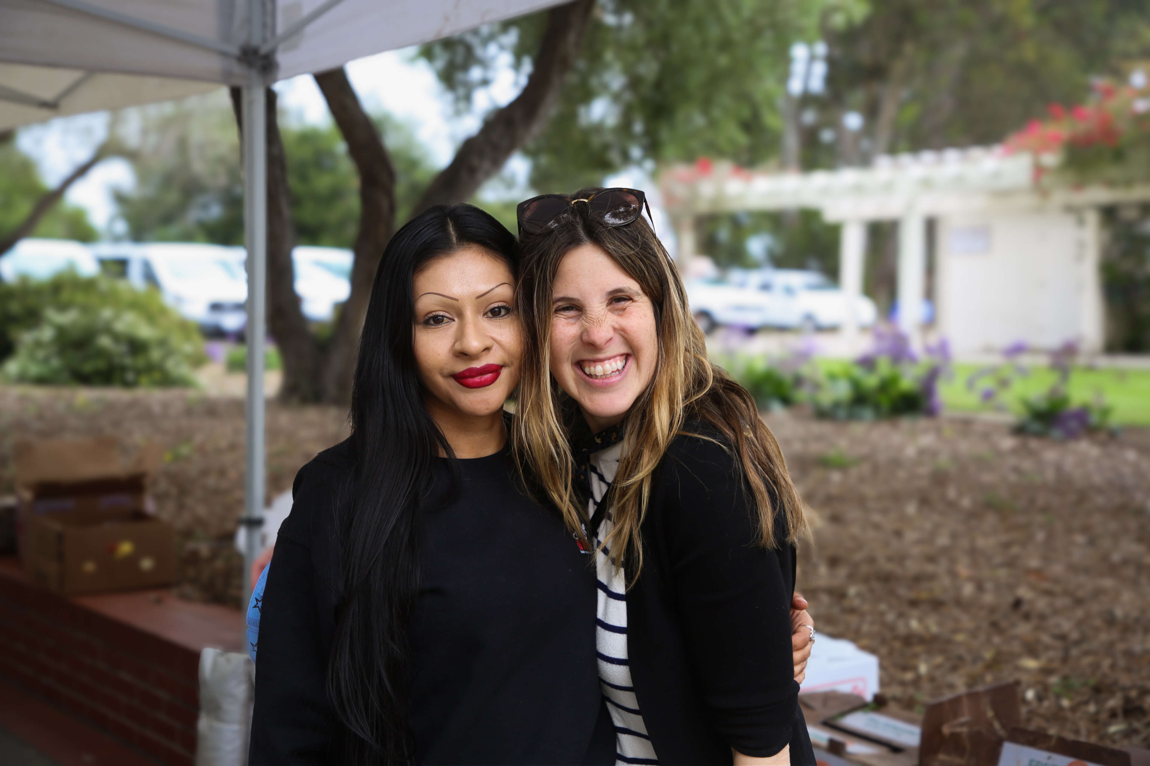 Two smiling women with arms around each other outdoors on a college campus